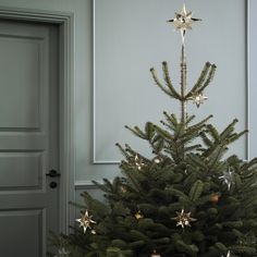 a small christmas tree in front of a door with ornaments on it's branches