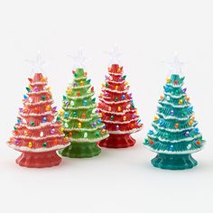 three brightly colored christmas trees are in the shape of small trees with lights on them