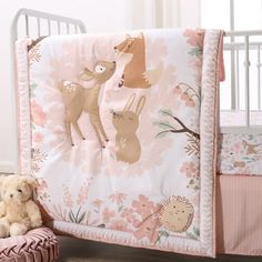 a teddy bear sitting next to a baby crib with pink and white bedding