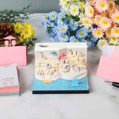 a table topped with cards and flowers next to a vase filled with flowers on top of a white counter