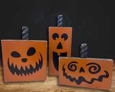 three wooden blocks with carved pumpkin faces and jack - o - lantern faces on them