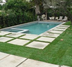 a pool surrounded by grass and lawn furniture