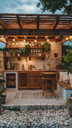 an outdoor kitchen is lit up with lights and potted plants