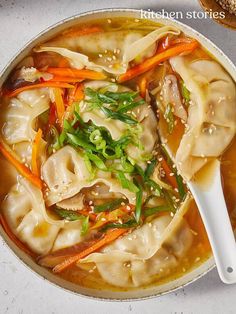 a bowl filled with dumplings and carrots on top of a white countertop