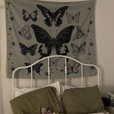 a white bed topped with pillows and a blanket covered in butterfly wall hanging above it