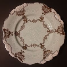 an ornately decorated plate sits on a black tablecloth with brown and white designs