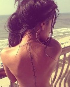 a woman with her back turned to the camera, looking out at the beach and ocean