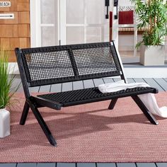 a black bench sitting on top of a pink rug next to a potted plant