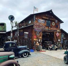 an old time gas station with antique cars and trucks parked in front of the building