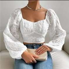 a woman sitting on top of a white couch wearing jeans and a cropped shirt