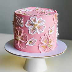 a pink cake decorated with flowers and pearls