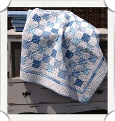 a blue and white quilt sitting on top of an old dresser