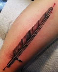 a black and white photo of a feather tattoo on the leg