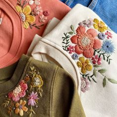 four different colored sweaters with flowers on them