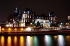 the city is lit up at night with lights reflecting in the water and buildings on both sides