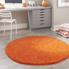 an orange rug is in front of a computer desk