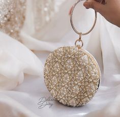 Introducing our luxurious Beaded Bridal Clutch, meticulously crafted to elevate your style on your special occasion. This exquisite accessory boasts premium quality velvet adorned with intricate beadwork and dazzling crystal embellishments, adding a touch of opulence to your ensemble. Designed with both elegance and functionality in mind, our round clutch features a plush suede lining that offers a soft and luxurious feel while ensuring the durability of the piece. The rich velvet exterior exude Elegant Festive Bridal Accessories, Festive Gold Clutch With Pearl Handle, Gold Beaded Clutch For Wedding, Wedding Gold Beaded Clutch, Elegant Handwork Jewelry For Festive Occasions, Gold Jewelry With Handwork For Party, Elegant Handwork Jewelry For Wedding, Gold Handwork Jewelry For Parties, Elegant Handwork Jewelry For Party