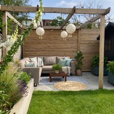 an outdoor living area with couches, tables and potted plants on the grass