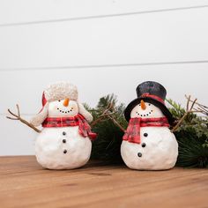 two snowmen with hats and scarfs on their heads are sitting next to each other