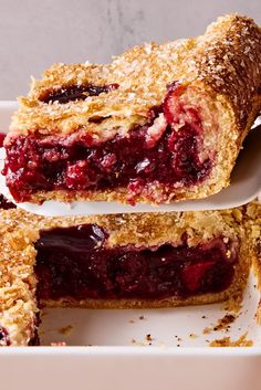 two pieces of berry pie sitting on top of a white plate next to each other