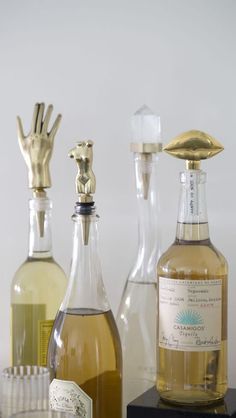 three different types of wine bottles with gold hand sculptures on the top one and bottom one