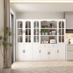 a kitchen with white cabinets and wood flooring next to a potted palm tree