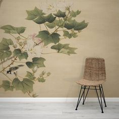 a chair sitting in front of a wall with flowers and leaves painted on the wall