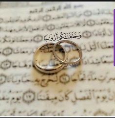 two wedding rings sitting on top of an open book with arabic writing in the background