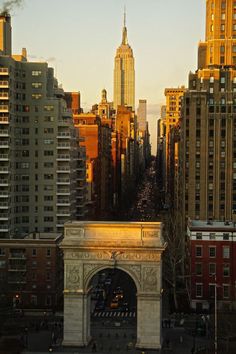 an arch in the middle of a city with tall buildings