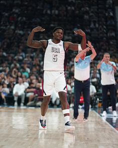 a man standing on top of a basketball court with his hands up in the air