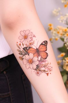 a woman's arm with a butterfly and flowers tattoo on the left side of her arm