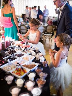 a group of people standing around a table filled with food