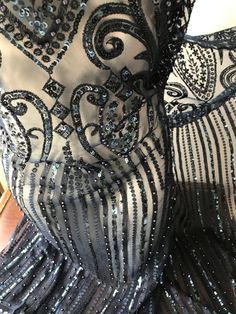 a black and silver dress with sequins on it's back, sitting on a wooden floor