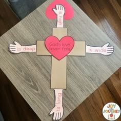 a cross made out of cardboard with hands holding a heart and the words god's love never folls