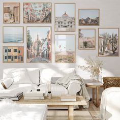 a living room filled with white furniture and pictures on the wall above it's coffee table