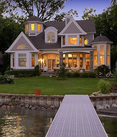 a large white house sitting on top of a lush green field next to a lake