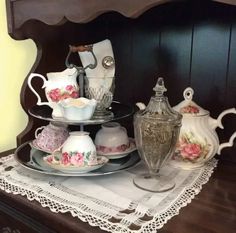 a table topped with plates and cups on top of a wooden table covered in doily