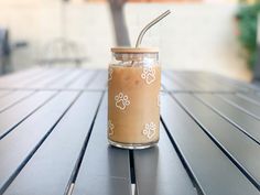 a glass jar with a straw in it sitting on a wooden table next to a tree