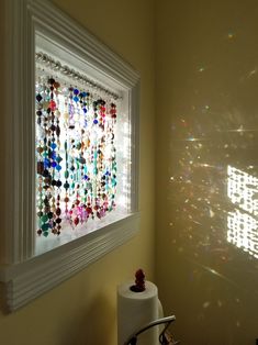 a bathroom with a white toilet and a colorful wall hanging on the wall next to it