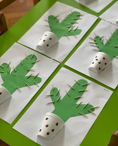 four paper cups with green leaves and dots on them are arranged in the shape of cactuses