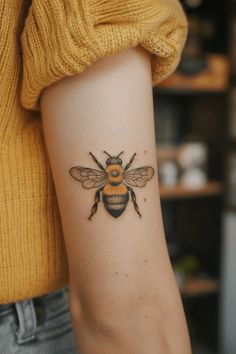 a woman's arm with a bee tattoo on it