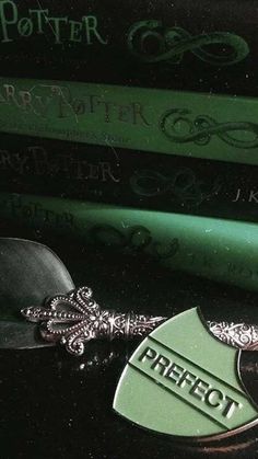 a green harry potter keychain sitting on top of three bookends next to each other