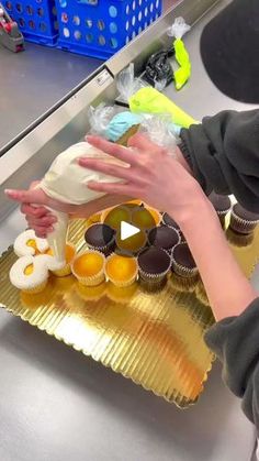 a person reaching for some cupcakes on a gold platter in a kitchen