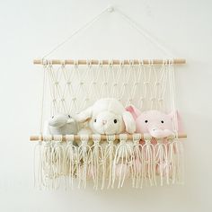 three stuffed animals are in a hammock hanging on the wall with ropes and yarn