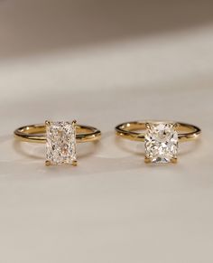 three different types of engagement rings sitting on a white surface with one diamond in the middle