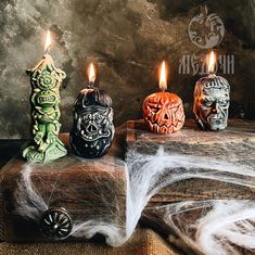 three halloween candles sitting on top of a wooden box with spider webs around them