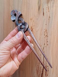 a hand holding a pair of wrenches in front of a wooden wall with wood planks