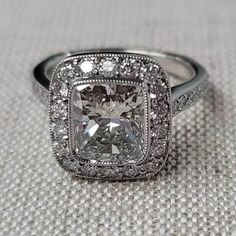 a cushion cut diamond ring with pave set diamonds on the band and sidestones