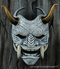 a mask with horns on it is shown in front of a black background and wood