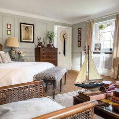 a bed room with a neatly made bed and a sailboat on the table next to it